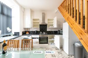 a kitchen with white cabinets and a wooden staircase at Cosy 2BR House in Bolton with Free WiFi & Parking in Bolton