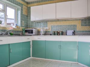 a kitchen with blue and white cabinets and a microwave at Botany Bay Bungalow in Kingsgate +11 photos