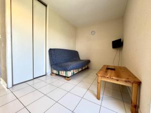 a room with a blue chair and a table at La Vallée Appartement 35 - Thermes Neyras les Bains in Meyras