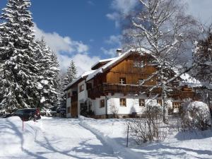 une grande maison en bois dans la neige avec des arbres dans l'établissement Landhaus Fiausch, à Mallnitz