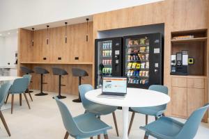 Un espacio de trabajo con una mesa, sillas y una computadora portátil. en easyHotel Madrid Alcala, en Madrid