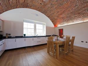 a kitchen with a table with chairs and a brick ceiling at The Sergeants Quarters, Golden Hill Fort in Freshwater