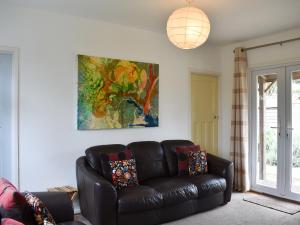 un soggiorno con divano in pelle e un dipinto di Cockle Cottage a Middleton-on-Sea