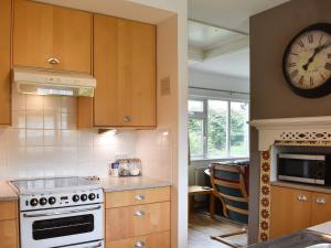 una cucina con piano cottura e orologio a muro di Cockle Cottage a Middleton-on-Sea
