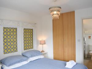 una camera da letto con un letto blu e un lampadario di Cockle Cottage a Middleton-on-Sea Altre 18 foto