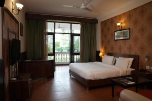 a hotel room with a bed and a large window at Naturoville Wellness Resort Rishikesh - Surrounded by Nature, Rooted in Wellness in Doiwāla