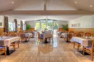 uma sala de jantar com mesas, cadeiras e janelas em Gasthof Waldhof em Dellach im Drautal