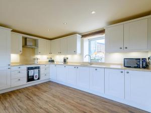 a kitchen with white cabinets and a wooden floor at Stable View in Peak Forest