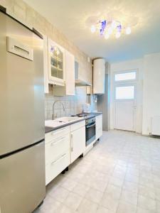 une cuisine avec des armoires blanches et un réfrigérateur en acier inoxydable dans l'établissement Comfortable 5BR Apt Well Connected Location, à Vienne