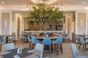 um restaurante com mesas e cadeiras e uma árvore em Radisson Resort Ruza Vjetrova em Dobra Voda
