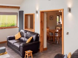 ein Wohnzimmer mit einer Ledercouch und einem Tisch in der Unterkunft Heyope Cottage in Llangunllo