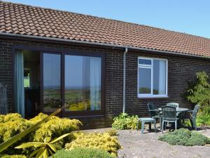 a house with a patio with a table and chairs at Eider Cottage in Embleton