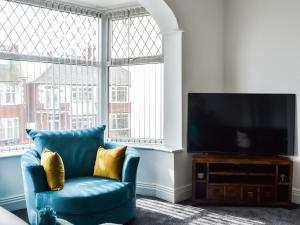 Una sala de estar con una silla azul y un televisor de pantalla plana. en Seaforth House, en Bridlington