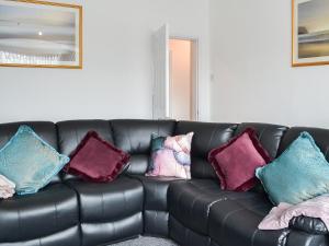 Un sofá de cuero negro con almohadas coloridas. en Seaforth House, en Bridlington