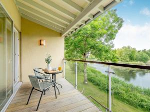 een balkon met een tafel en uitzicht op een rivier bij Plovers Nest At Lower Mill in Somerford Keynes