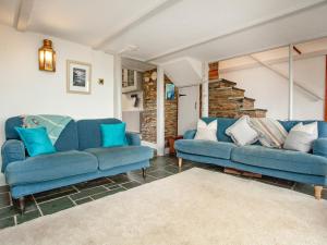 een woonkamer met twee blauwe banken en een stenen muur bij Railway Cottage in Camelford
