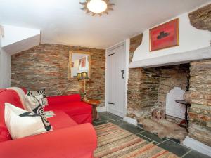 een woonkamer met een rode bank en een bakstenen muur bij Railway Cottage in Camelford