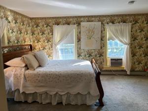 a bedroom with a bed and two windows at Aiken Manor B&B in Franklin
