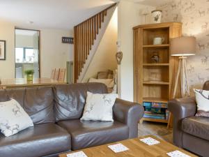 a living room with a leather couch and a table at Wood-Side Cottage in Backbarrow