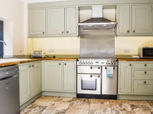 a kitchen with white cabinets and a stove at Wood-Side Cottage in Backbarrow +8 photos