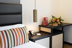 a bed with a nightstand with a phone and flowers at Warmthotel in Rome