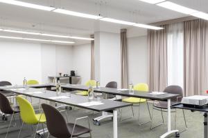 a conference room with long tables and yellow chairs at Warmthotel in Rome
