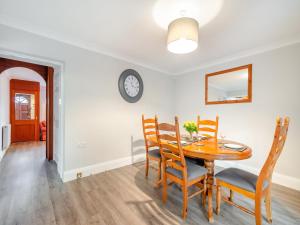 a dining room with a table and chairs and a clock on the wall at Bow Cottage in Pickering