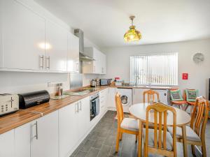 Una cocina con gabinetes blancos y una mesa y sillas. en The Bungalow, en Denby