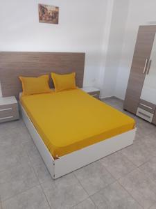 a bedroom with a bed with yellow sheets and pillows at Dar Marhaba bis karkouane in Kerkouene