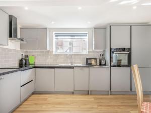 a white kitchen with white cabinets and a window at Two Little Ducks in Wells next the Sea