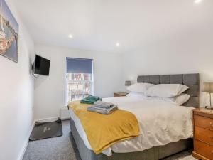a bedroom with a bed with a yellow blanket on it at Two Little Ducks in Wells next the Sea +5 photos