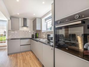 a kitchen with white cabinets and stainless steel appliances at Two Little Ducks in Wells next the Sea