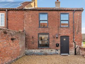 a brick building with a black door and windows at Two Little Ducks in Wells next the Sea