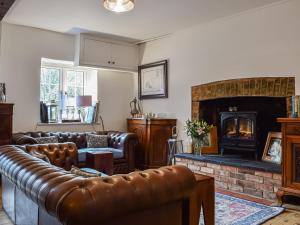 a living room with leather furniture and a fireplace at Burwood Cottage in Rotherfield Peppard