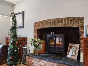 a living room with a christmas tree and a fireplace at Burwood Cottage in Rotherfield Peppard