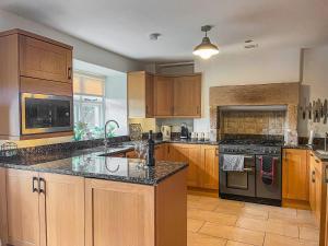 a kitchen with wooden cabinets and a stove top oven at Acacia Cottage in Wirksworth