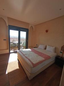 ein Schlafzimmer mit einem Bett und ein Balkon mit einem Tisch in der Unterkunft Mirleft Horizon Suites in Mirleft