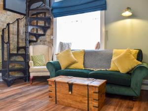 ein Wohnzimmer mit einem grünen Sofa und einem Holztisch in der Unterkunft Beck View Cottage in Staithes