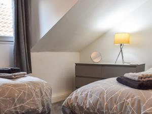 a bedroom with two beds and a dresser and a window at Jet Workers Cottage in Whitby