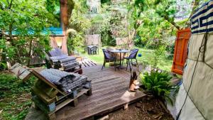 a wooden deck with a table and chairs in a yard at La Yourte climatisée du Jardin Caché in Marmande