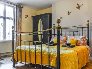 a bedroom with a black bed with a yellow bedspread at Half Pint Cottage in Haworth