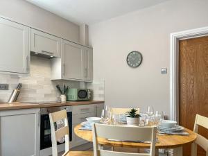 a kitchen with a table and a clock on the wall at Alders Cottage in Tansley