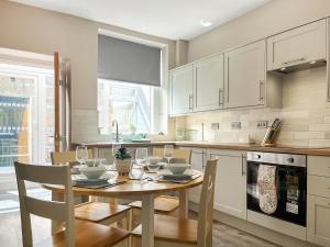 a kitchen with a wooden table with chairs and a dining room at Alders Cottage in Tansley