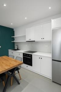 サランダにあるSasori Apartmentsの白いキャビネットと木製のテーブルのあるキッチン