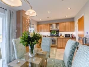 eine Küche mit einem Glastisch und blauen Stühlen in der Unterkunft Kittiwake in Amble