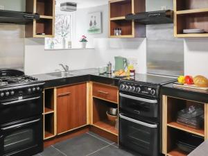 eine Küche mit schwarzen Geräten und Holzschränken in der Unterkunft Rhiw Farmhouse in Llangelynin