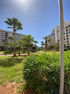 a park with palm trees and a building at Luxurious and modern 2BR with View and Pool in Beni Brour