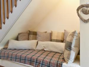 a pile of pillows on a couch under the stairs at Wood-Side Cottage in Backbarrow