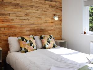 a bedroom with a white bed with a wooden wall at Peris Lodge - Uk47606 in Caernarfon +5 photos