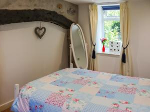 ein Schlafzimmer mit einem Bett und einem Spiegel in der Unterkunft Orchard Cottage in Pwllheli + 6 Fotos